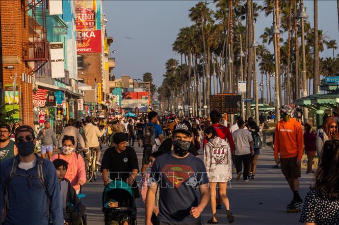Trong ảnh: Người dân đi dạo trên bãi biển ở California, Mỹ sau khi lệnh hạn chế nhằm ngăn dịch COVID-19 lây lan được nới lỏng, ngày 22/5/2020. Ảnh: AFP/TTXVN