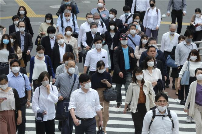 Trong ảnh: Người dân đeo khẩu trang phòng dịch COVID-19 khi di chuyển trên phố ở Tokyo, Nhật Bản ngày 26/5/2020. Ảnh: AFP/TTXVN
