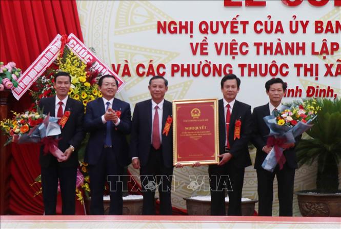 Trong ảnh: Chủ tịch UBND tỉnh Bình Định Hồ Quốc Dũng (thứ 2 từ trái) trao Nghị quyết số 932/NQ-UBTVQH14 của Ủy ban Thường vụ Quốc hội về việc thành lập Thị xã Hoài Nhơn và các phường thuộc thị xã Hoài Nhơn cho lãnh đạo Huyện ủy, UBND huyện Hoài Nhơn. Ảnh: Phạm Kha – TTXVN
