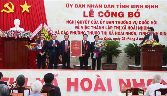 Trong ảnh: Chủ tịch UBND tỉnh Bình Định Hồ Quốc Dũng (thứ 2 từ trái) trao Nghị quyết số 932/NQ-UBTVQH14 của Ủy ban Thường vụ Quốc hội về việc thành lập thị xã Hoài Nhơn và các phường thuộc thị xã Hoài Nhơn cho lãnh đạo Huyện ủy, UBND huyện Hoài Nhơn. Ảnh: Phạm Kha – TTXVN.