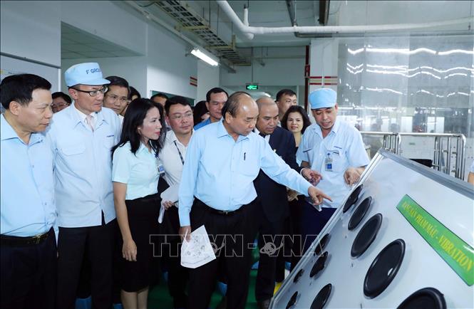 Trong ảnh: Thủ tướng Nguyễn Xuân Phúc xem các sản phẩm của Công ty TNHH Điện tử Foster (Việt Nam).  Ảnh: Thống Nhất – TTXVN