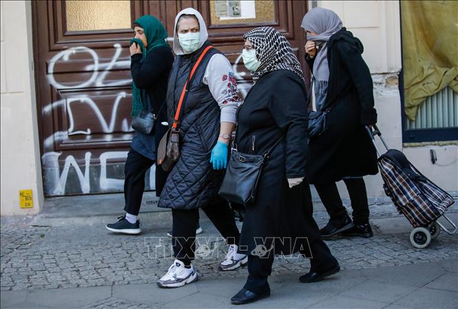 Trong ảnh: Người dân đeo khẩu trang phòng dịch COVID-19 tại Berlin, Đức ngày 17/4/2020. Ảnh: AFP/TTXVN