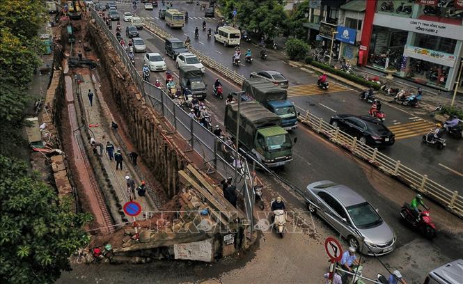 Trong ảnh: Dự án sẽ hạ cao độ đường Âu Cơ để thay thế một phần kết cấu đê đất bằng tường bê tông cốt thép (phía ngoài đê), kết hợp với mở rộng mặt đường đê, cải tạo và chỉnh trang hệ thống đường gom dân sinh, xây dựng tường chắn tại vị trí dải phân cách giữa mặt đường chính để xử lý chênh cao độ giữa hai làn đường. Ảnh: Thành Đạt - TTXVN 
