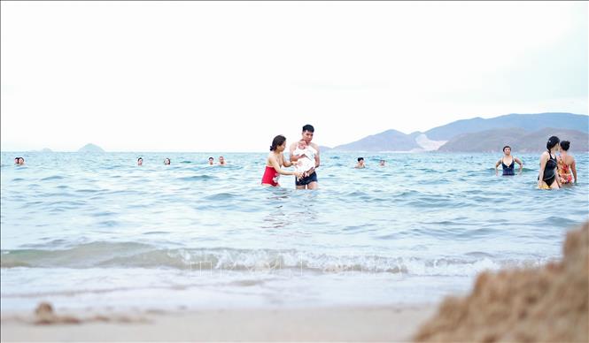 Trong ảnh: Cả gia đình nhỏ cùng xuống tắm biển giải nhiệt. Ảnh: Nguyễn Dũng – TTXVN