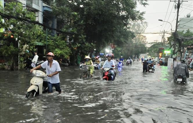 Trong ảnh: Ngập sâu trên đường Phan Anh (Quận 2) khiến người dân phải xuống xe dắt bộ. Ảnh: Hồng Giang - TTXVN