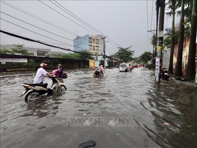 Trong ảnh: Người dân di chuyển khó khăn vì nước ngập sâu trên đường Nguyễn Duy Trinh (Quận 2). Ảnh: Hồng Giang - TTXVN.