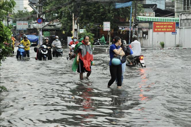 Trong ảnh: Người dân gặp khó khăn khi di chuyển giữa là nước ngập trên đường Phan Anh (Quận 2). Ảnh: Hồng Giang - TTXVN.