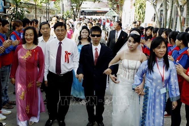 Trong ảnh: Lãnh đạo Trung tâm Nhân đạo Quê Hương, tỉnh Bình Dương (bên trái) tổ chức lễ cưới tập thể cho 12 cặp vợ chồng là nạn nhân chất độc da cam/điôxin, khiếm thị và khuyết tật vận động, hiện đang sinh sống và làm việc tại Trung tâm (2014). Ảnh: Thế Anh – TTXVN