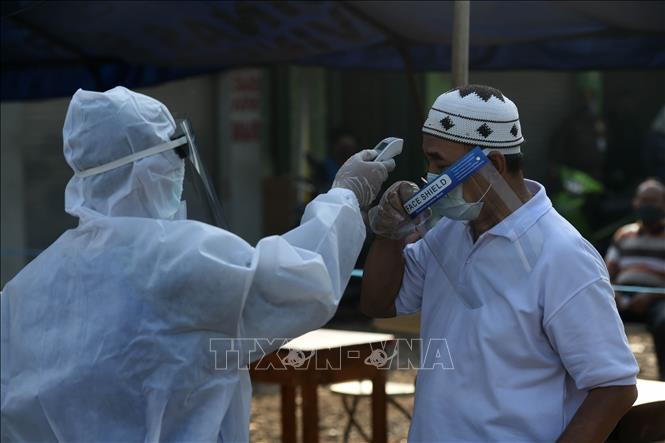 Trong ảnh: Nhân viên y tế kiểm tra thân nhiệt cho người dân ở Jakarta, Indonesia nhằm ngăn dịch COVID-19 lây lan, ngày 25/6/2020. Ảnh: THX/TTXVN