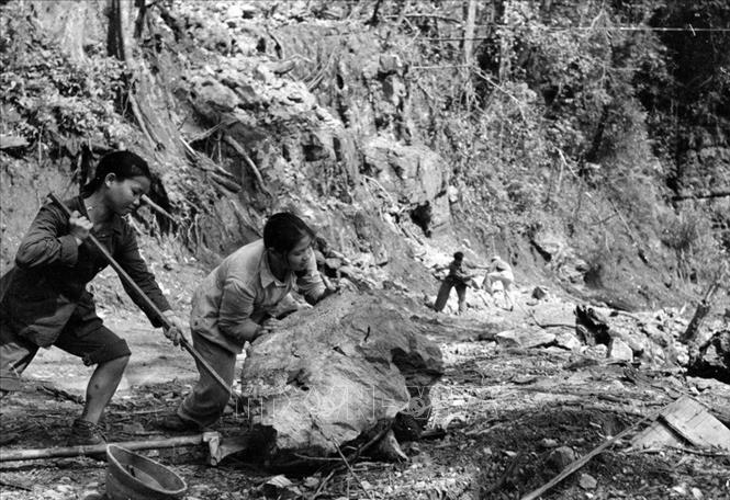 Trong ảnh: TNXP đẩy đá, mở đường cho xe qua trên tuyến đường Trường Sơn. Ảnh: Hữu Ngôi – TTXVN