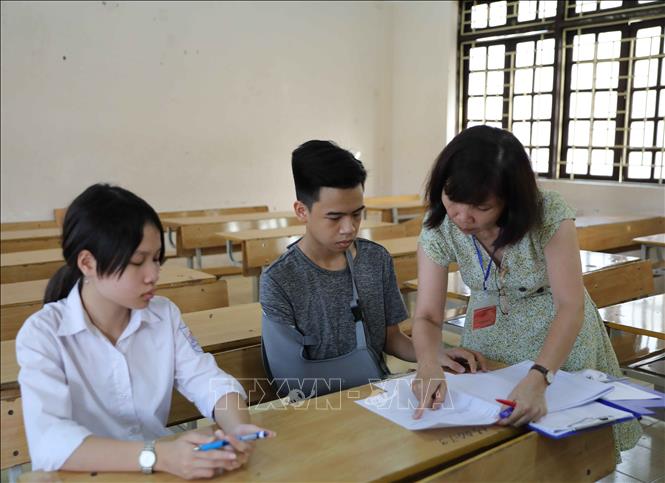 Trong ảnh: Hội đồng thi tại điểm thi Trường THPT Cầu Giấy hướng dẫn thí sinh đặc biệt (bị gãy tay, có bạn viết bài hộ) cách thức làm bài thi theo đúng quy chế. Ảnh: Thanh Tùng - TTXVN