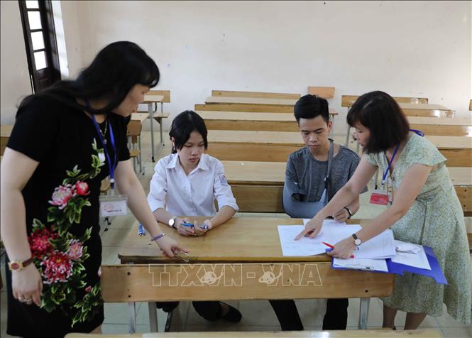 Trong ảnh: Giám thị Hội đồng thi Trường THPT Cầu Giấy hướng dẫn thí sinh đặc biệt (bị gãy tay, có bạn viết bài hộ) cách thức làm bài thi theo đúng quy chế. Ảnh: Thanh Tùng - TTXVN
