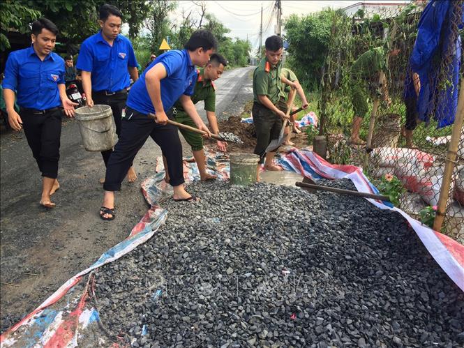 Trong ảnh: Đoàn viên, thanh niên tham gia thực hiện công trình tuyến đường hoa thanh niên và thắp sáng đường giao thông nông thôn tại xã Mỹ Tịnh An, huyện Chợ Gạo. Ảnh: Hữu Chí-TTXVN