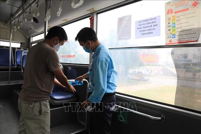 Trong ảnh: Phụ xe buýt hướng dẫn khách rửa tay bằng dung dịch sát khuẩn khi lên xe. Ảnh: Thành Đạt - TTXVN