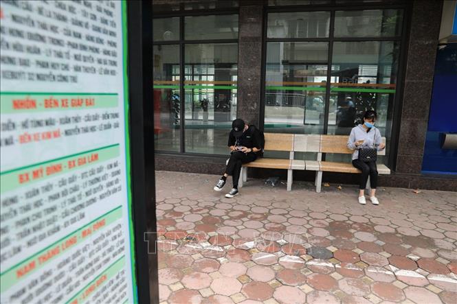 Trong ảnh: Tại các bến hoặc điểm chờ xe buýt, người dân được yêu cầu thực nghiêm việc đeo khẩu trang và giãn khoảng cách cần thiết. Ảnh: Thành Đạt - TTXVN 