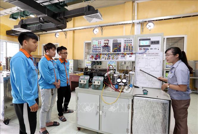 Trong ảnh: Giảng viên Nguyễn Thị Thơm hướng dẫn sinh viên quan sát trên thiết bị giải thích sơ đồ nguyên lý, nguyên lý hoạt động của mô hình hệ thống máy lạnh ghép tầng. Ảnh: Anh Tuấn – TTXVN