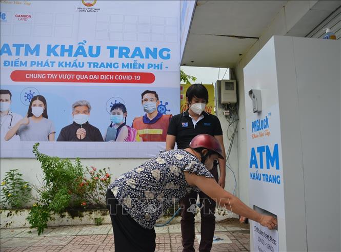 Photo: The ATM's invetor Hoang Tuan Anh guides people how to get face masks. VNA Photo: Hứa Chung