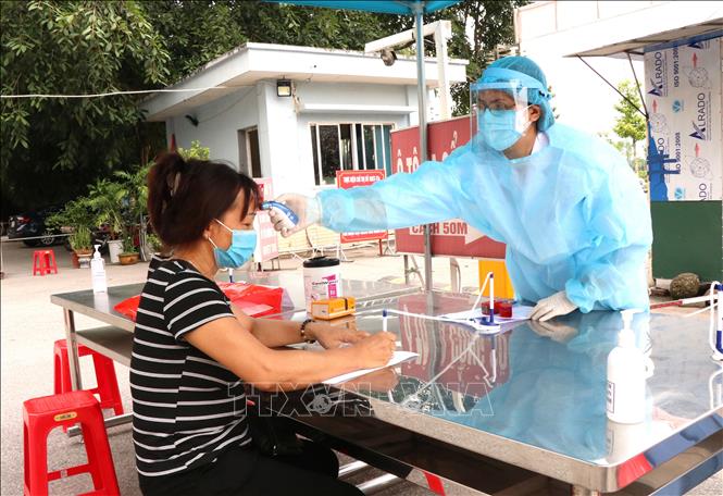 Trong ảnh:Bác sỹ Bệnh viện đa khoa tỉnh Bắc Ninh đo thân nhiệt cho bệnh nhân đến thăm, khám. Ảnh: Đinh Văn Nhiều-TTXVN