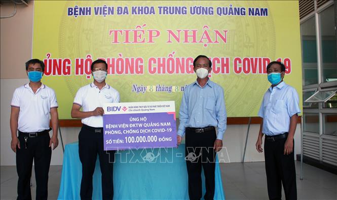 Trong ảnh: Đại diện BIDV Chi nhánh Quảng Nam trao tượng trưng số tiền ủng hộ 100 triệu đồng cho Bệnh viện Đa khoa Trung ương Quảng Nam, nơi điều trị trực tiếp cho các bệnh nhân mắc COVID-19. Ảnh: Trần Tĩnh - TTXVN