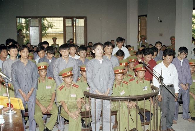 Tháng 5/1996, Cục Cảnh sát hình sự (Bộ Công an) lập chuyên án mang bí số K596, quét sạch băng nhóm tội phạm có tổ chức do Dương Văn Khánh (tức Khánh trắng) cầm đầu về các tội cưỡng đoạt tài sản, thu tiền “bảo kê” tại chợ Long Biên (quận Ba Đình, Hà Nội). Trong ảnh: Bị cáo Dương Văn Khánh và 23 bị cáo đứng trước vành móng ngựa tại phiên tòa xét xử (5/9/1997). Ảnh: Minh Điền – TTXVN