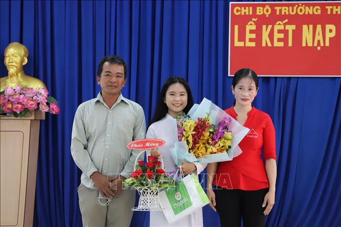 Trong ảnh: Em Giang Thị Mộng Như cùng bố mẹ tại Lễ kết nạp. Ảnh: Hồng Giang - TTXVN. 