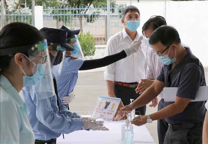 Trong ảnh: Đo nhiệt độ, rửa tay sát khuẩn và bật ứng dụng Bluezone trước khi vào khu vực sản xuất, lao động. Ảnh: Quốc Dũng - TTXVN