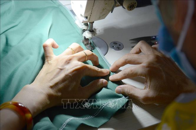 Trong ảnh: Mỗi bộ quần áo được các chị nâng niu, cẩn thận, gửi gắm tình thương, sự trân quý trong từng đường kim, mũi chỉ. Ảnh: Quốc Dũng – TTXVN