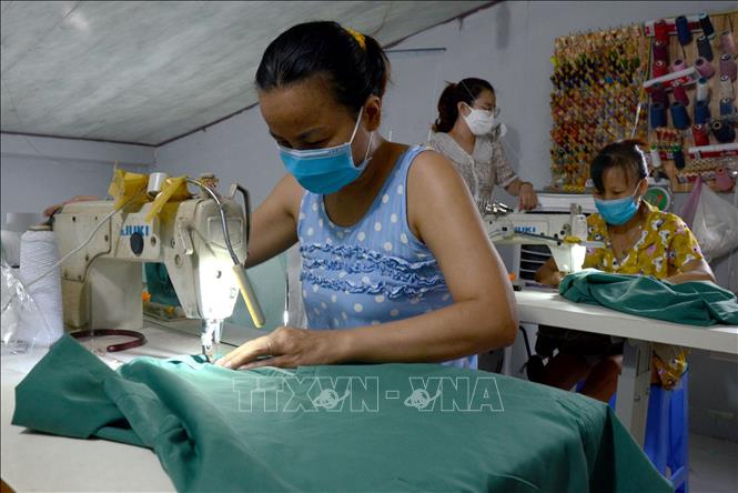 Trong ảnh: Các máy khâu được bố trí khoảng cách hợp lý, người ngồi may quay lưng với nhau để đảm bảo giãn cách. Ảnh: Quốc Dũng – TTXVN
