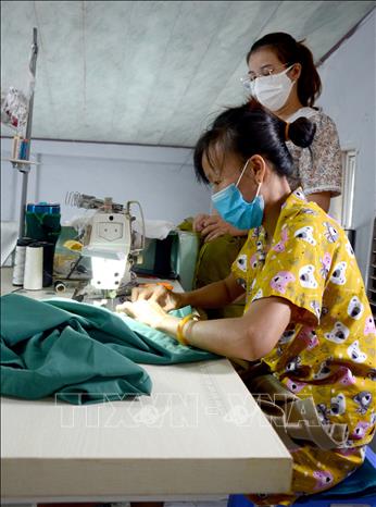 Trong ảnh: Chị Nguyễn Thị Thùy Vân (42 tuổi, Hội viên Chi hội phụ nữ số 15) điều kiện kinh tế vốn đã khó khăn, thu nhập không ổn định, nhưng vẫn rất hăng hái, là người đầu tiên hưởng ứng chương trình may quần áo cho bác sỹ. Ảnh: Quốc Dũng – TTXVN