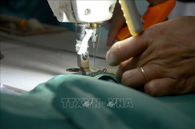 Trong ảnh: Mỗi bộ quần áo được các chị nâng niu, cẩn thận, gửi gắm tình thương, sự trân quý trong từng đường kim, mũi chỉ. Ảnh: Quốc Dũng – TTXVN