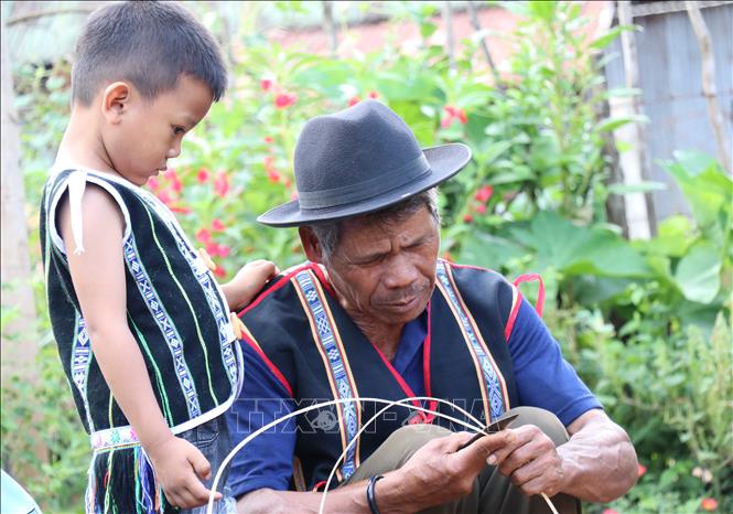 Trong ảnh: Các cháu bé chăm chú nhìn theo công đoạn làm gùi của ông mình. Ảnh: Hồng Điêp - TTXVN 