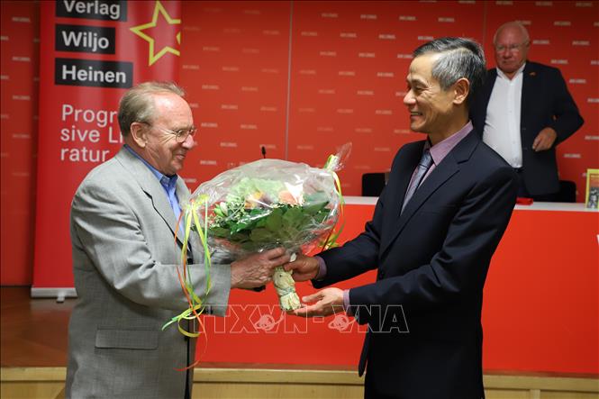 Trong ảnh: Đại sứ Nguyễn Minh Vũ tặng hoa tác giả Hellmut Kapfenberger trong buổi lễ ra mắt cuốn sách “Tiểu sử chính trị Hồ Chí Minh
