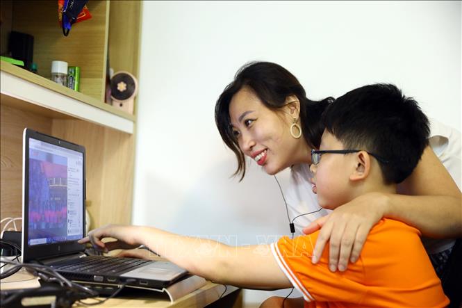 Trong ảnh: Các học sinh dự khai giảng tại nhà qua màn ảnh nhỏ cùng phụ huynh. Ảnh: Huy Hùng - TTXVN  