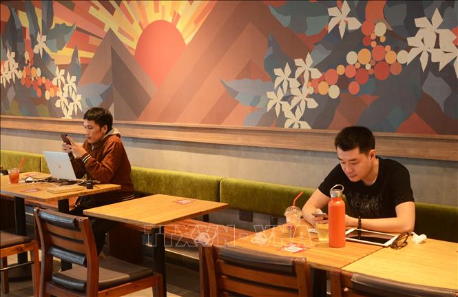 Trong ảnh: Khách hàng tự giác ngồi giãn cách tại quán cà phê. Ảnh: Văn Dũng - TTXVN