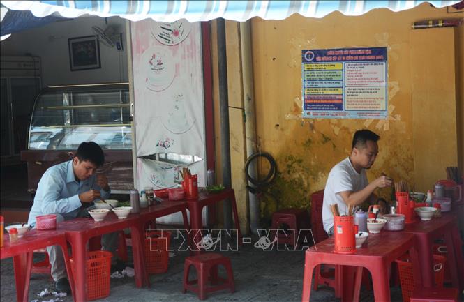 Trong ảnh: Khách ăn sáng tại quán bún ven đường Hoàng Văn Thụ (phường Phước Ninh, quận Hải Châu) tuân thủ việc ngồi giãn. Ảnh: Văn Dũng - TTXVN