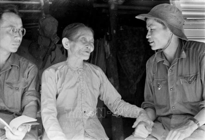 Trong ảnh: Phóng viên Thanh Phong của TTXGP tại Quảng Trị (bên phải) nói chuyện với một gia đình nuôi cán bộ cách mạng tại thị xã Quảng Trị (1968). Ảnh: Tư liệu TTXGP