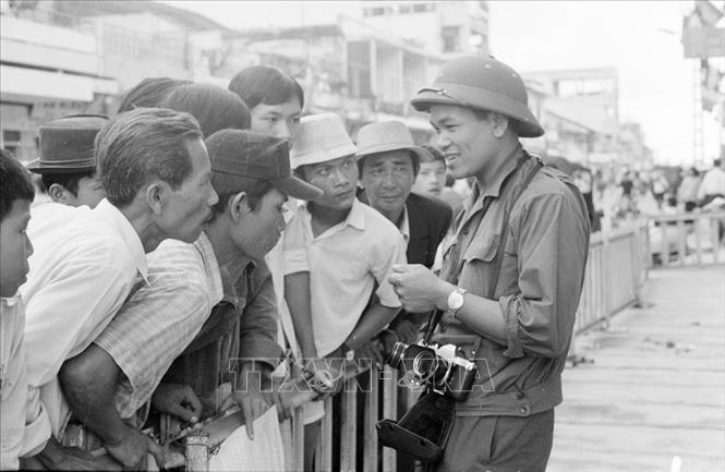 Trong ảnh: Phóng viên Hứa Kiểm của VNTTX gặp gỡ quần chúng nhân dân Sài Gòn để đưa tin, ảnh về thắng lợi của Chiến dịch Hồ Chí Minh lịch sử 1975, giải phóng hoàn toàn miền Nam, thống nhất đất nước. Ảnh: Tư liệu VNTTX
