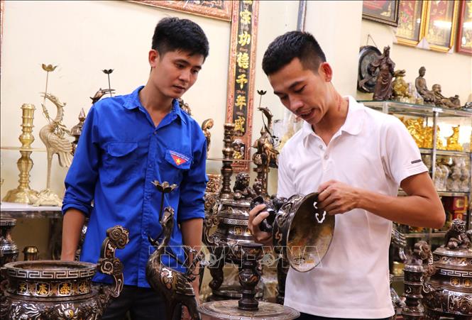 Trong ảnh: Thanh niên xã Đại Bái, huyện Gia Bình, tỉnh Bắc Ninh giới thiệu các mặt hàng đồ đồng mỹ nghệ. Ảnh: Đinh Văn Nhiều-TTXVN