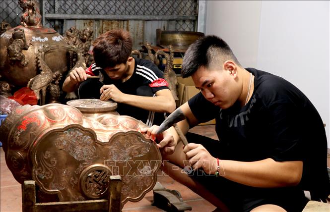 Trong ảnh: Thanh niên xã Đại Bái, huyện Gia Bình tỉnh Bắc Ninh thực hiện công đoạn khắc họa tiết, hoa văn cho sản phẩm đồ đồng. Ảnh: Đinh Văn Nhiều-TTXVN