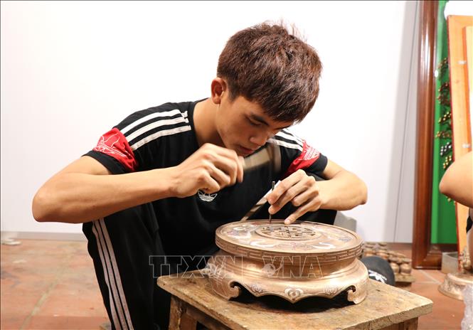 Trong ảnh: Thanh niên xã Đại Bái, huyện Gia Bình tỉnh Bắc Ninh thực hiện công đoạn khắc họa tiết, hoa văn cho sản phẩm đồ đồng. Ảnh: Đinh Văn Nhiều-TTXVN