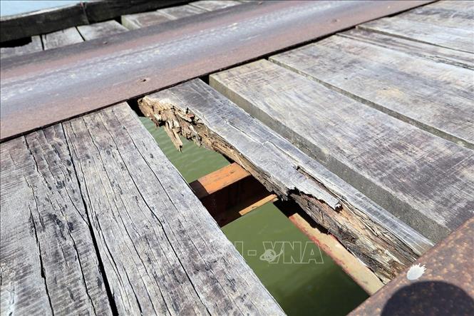 Trong ảnh: Những tấm gỗ ván đã bị mục nát, gãy tạo thành lỗ hổng trên mặt cầu. Ảnh: Phan Tuấn Anh - TTXVN