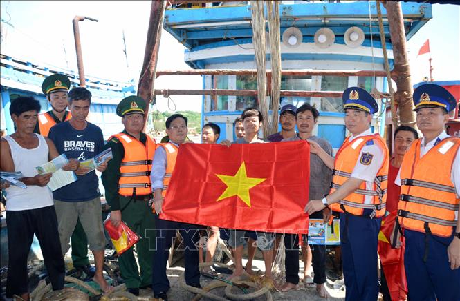 Trong ảnh: Thiếu tướng Bùi Quốc Oai tặng cờ Tổ quốc cho ngư dân tại âu cảng Bạch Long Vĩ. Ảnh: TTXVN