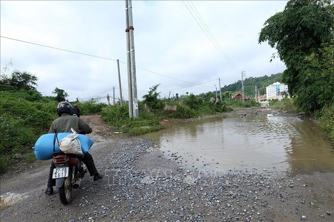 Trong ảnh: Người dân phải đi đường tránh qua vũng nước to đọng dưới mặt đường. Ảnh: Phan Tuấn Anh - TTXVN