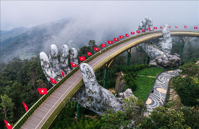 Trong ảnh: Cầu Vàng tại khu du lịch Bà Nà Hills được cắm cờ cờ Tổ quốc chào đón các du khách trở lại tham quan sau thời gian tạm nghỉ vì dịch. Ảnh: TTXVN phát