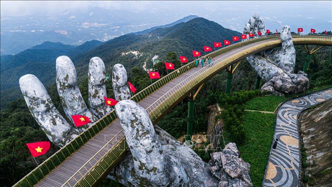 Trong ảnh: Cầu Vàng tại khu du lịch Bà Nà Hills được cắm cờ cờ Tổ quốc chào đón các du khách trở lại tham quan sau thời gian tạm nghỉ vì dịch. Ảnh: TTXVN phát