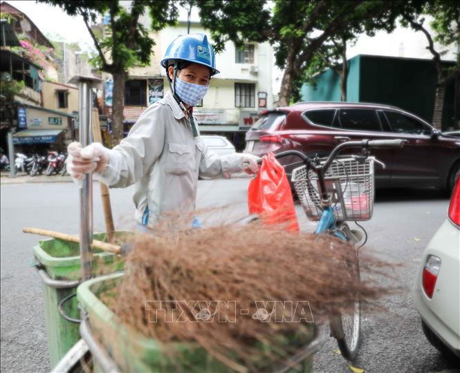 Trong ảnh: Với chiếc xe đạp và vật dụng quen thuộc (chổi, xẻng) người công nhân này đi sau các xe ô tô thu gom rác để làm sạch lần nữa nơi đặt các thùng rác trên phố. Ảnh: Thanh Tùng - TTXVN  