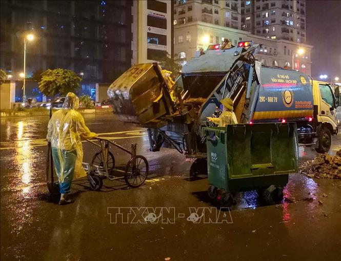 Trong ảnh: Bất kể mưa gió, việc thu gom rác thải của những người làm công tác vệ sinh môi trường vẫn diễn ra bình thường. Ảnh: Thanh Tùng - TTXVN