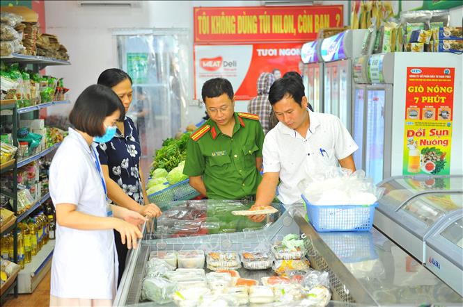 Đoàn kiểm tra ATVSTP kiểm tra thực phẩm và giấy tờ của các cửa hàng thực phẩm trên địa bàn thành phố Ninh Bình. Ảnh: Minh Đức - TTXVN