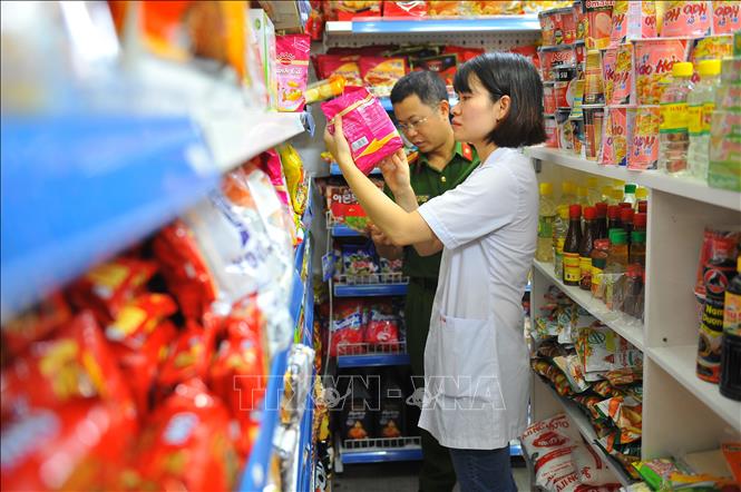 Đoàn kiểm tra ATVSTP kiểm tra thực phẩm và giấy tờ của các cửa hàng thực phẩm trên địa bàn thành phố Ninh Bình. Ảnh: Minh Đức - TTXVN