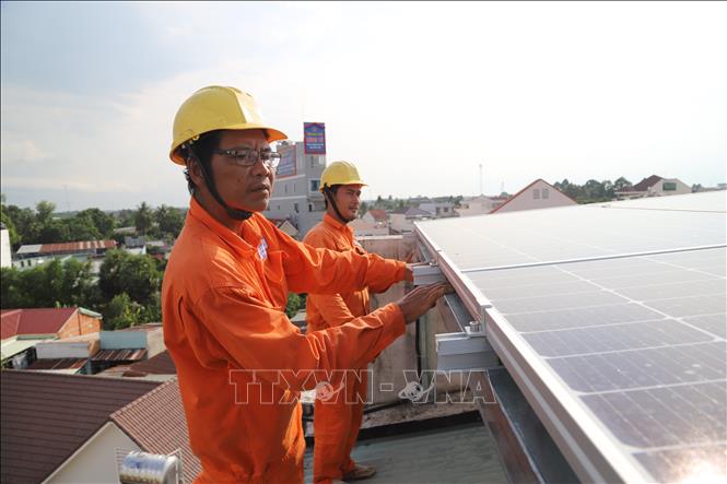 Trong ảnh: Công nhân Công ty Điện lực Thị xã Hòa Thành (Tây Ninh) kiểm tra hệ thống điện năng lượng mặt trời áp mái của người dân. Ảnh: Thanh Tân - TTXVN